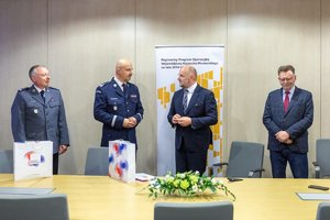 Przedstawiciele Komendy Wojewódzkiej Policji w Bydgoszczy oraz Urzędu Marszałkowskiego Województwa Kujawsko-Pomorskiego rozmawiający przy stole konferencyjnym, w tle baner z napisem Regionalny Program Operacyjny Województwa Kujawsko-Pomorskiego na lata 2014 - 2021. Fotografia: Szymon Zdziebło/tarantoga.pl dla Urzędu Marszałkowskiego Województwa Kujawsko-Pomorskiego
